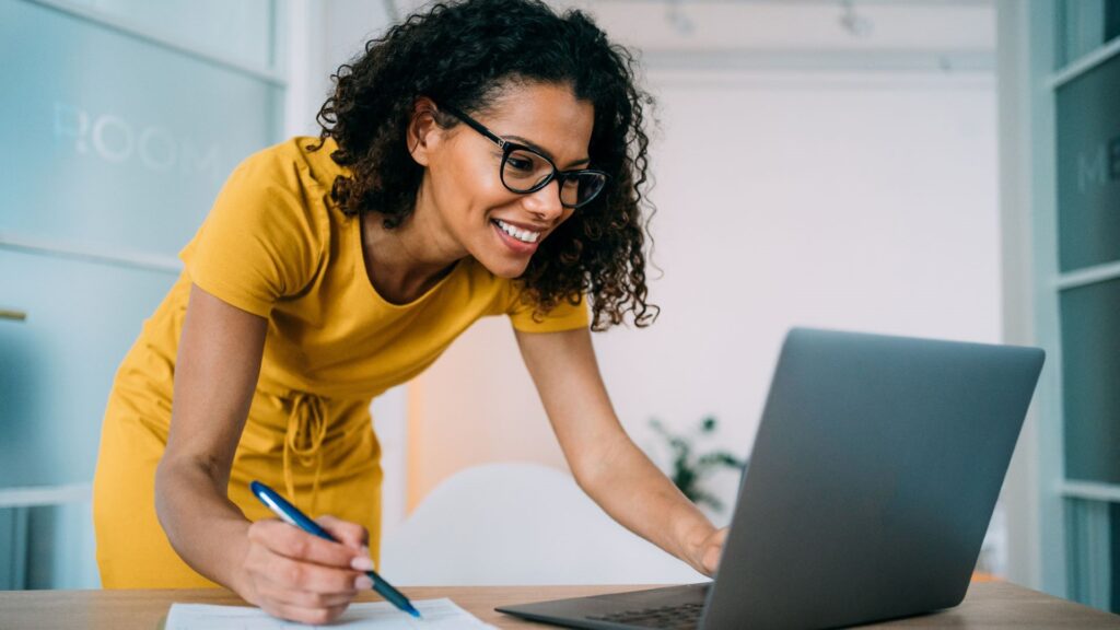 event planner looking at computer and writing on clipboard