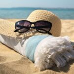 Sun hat, Sunglasses, and beach towel laying on the beach